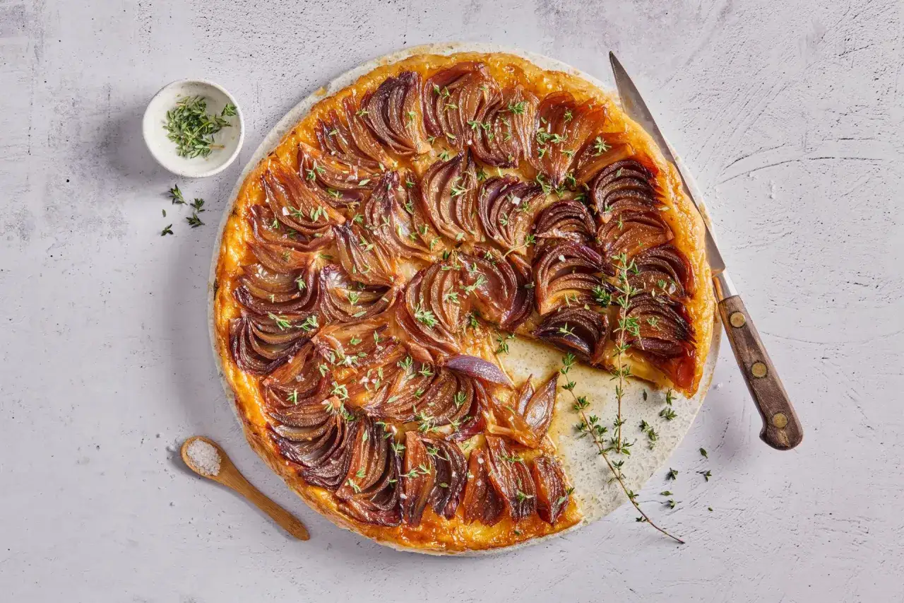 Herzhafte Zwiebel-Tarte Tatin, karamellisiert und mit Thymian garniert, bereit zum Servieren.