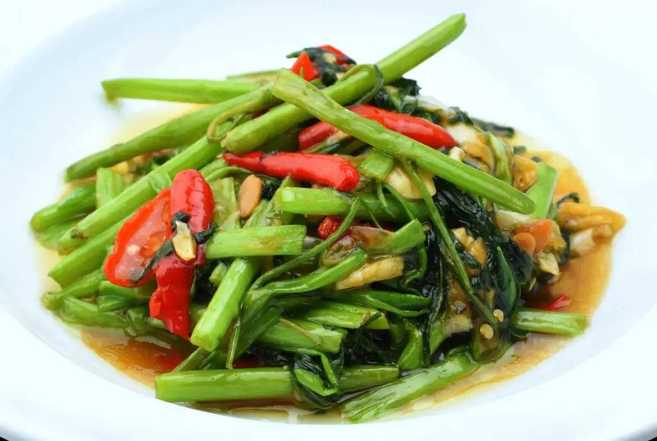 Gebratener Morning Glory Thai mit Chili und Knoblauch auf einem wei&szlig;en Teller.