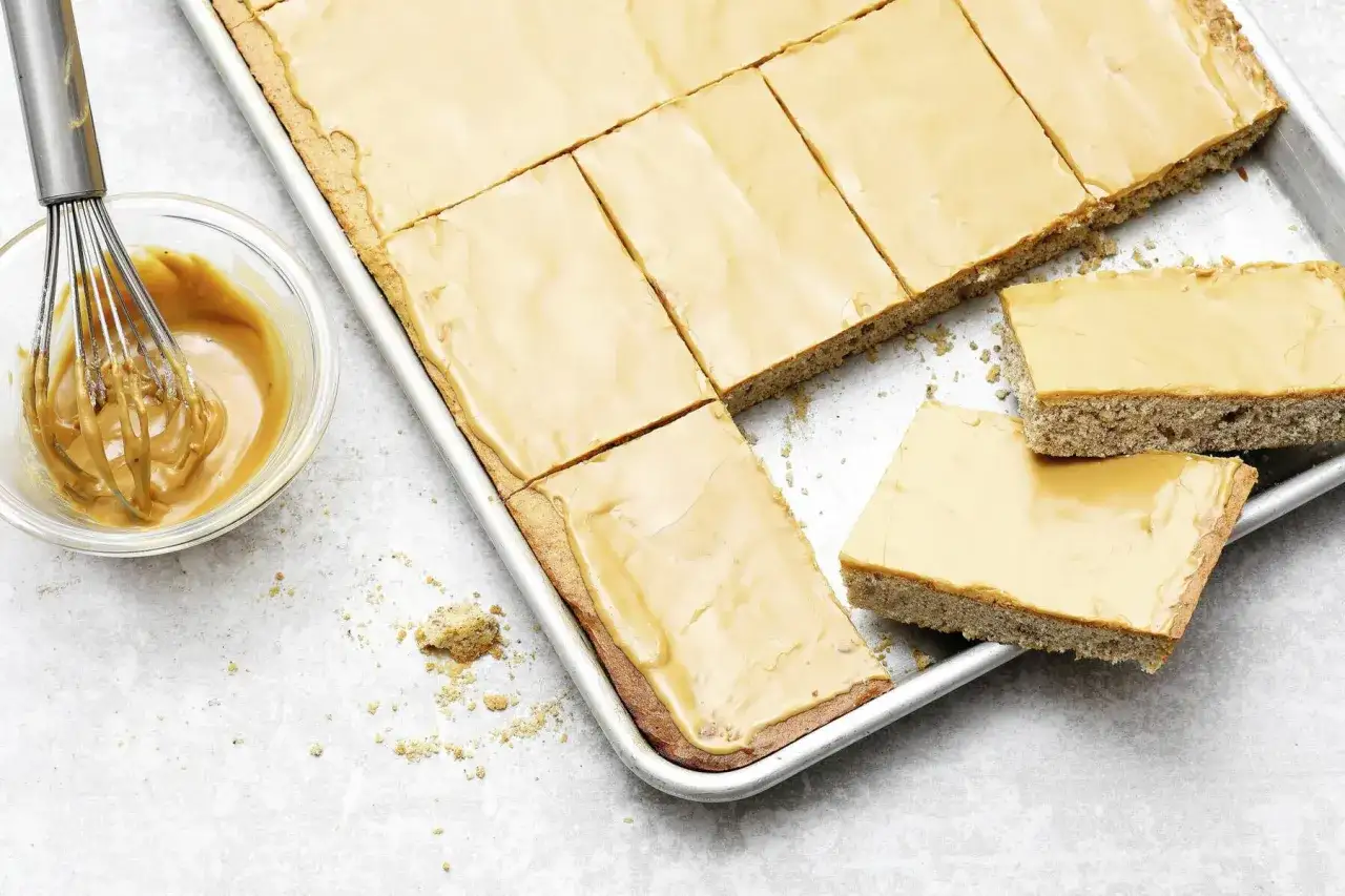 Blechkuchen mit heller Glasur, perfekt zum blechkuchen 3 tage vorher backen. Daneben eine Sch&uuml;ssel mit Schneebesen und Glasur.