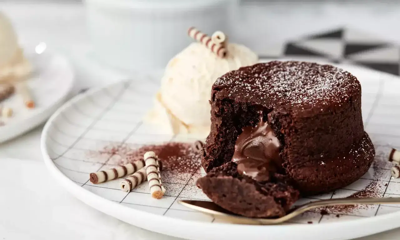 Ein saftiger Moelleux au Chocolat, deutsch f&uuml;r Schokoladenkuchen, mit fl&uuml;ssigem Kern, serviert mit Vanilleeis und Schokor&ouml;llchen.