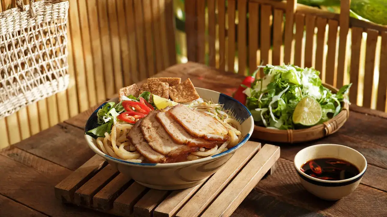 Cao Lầu: Nudelsch&uuml;ssel mit Schweinefleisch, Kr&auml;utern, Chili und Limette, serviert mit Dip.