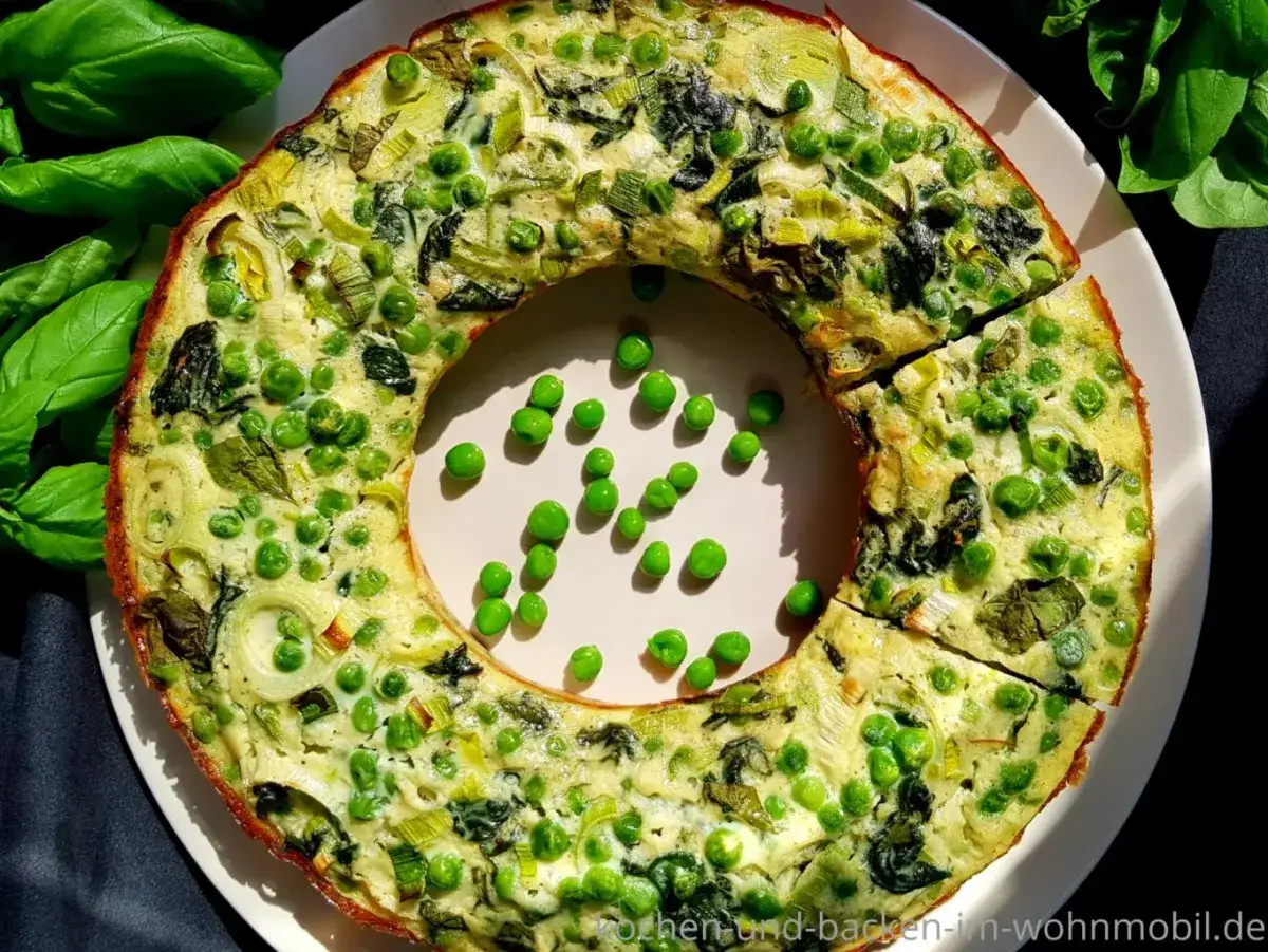 Herzhafte quiche ohne boden mit Erbsen und Lauch, goldbraun gebacken, auf einem Teller mit frischem Basilikum.