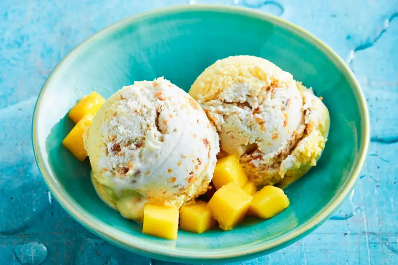 Zwei Kugeln Kokoseis mit Mango-St&uuml;ckchen in einer t&uuml;rkisfarbenen Schale. Perfekt zum kokoseis selber machen mit eismaschine.