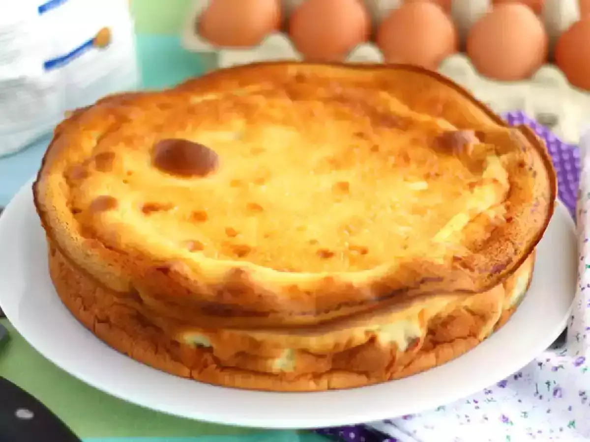 Goldbrauner, aufgegangener Far Breton auf einem Teller, daneben Eier und eine Packung Mehl.