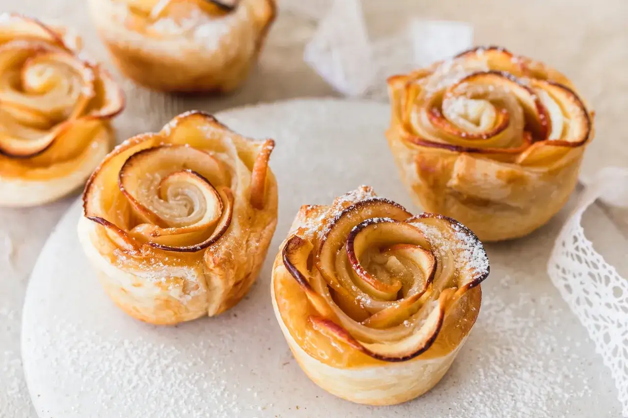 Goldbraune Apfelrosen, perfekt zum Vortag backen, mit Puderzucker best&auml;ubt.