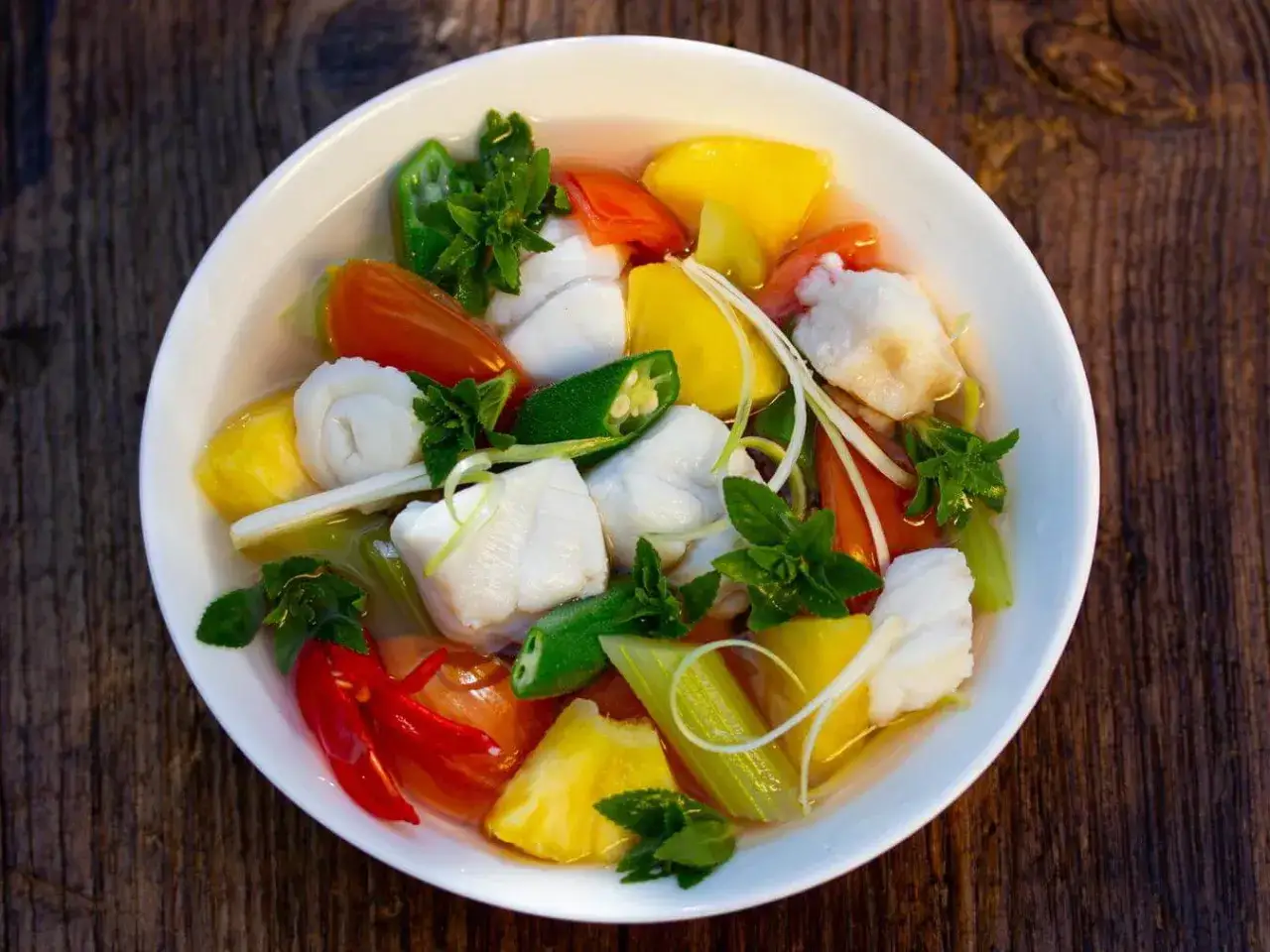 Ein Sch&uuml;ssel Canh Chua mit Fisch, Ananas, Tomaten, Okra und Kr&auml;utern.