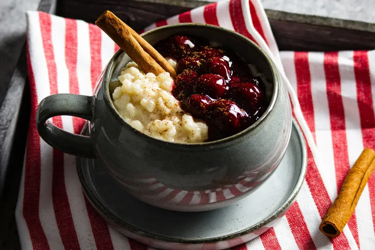 Cremiger Milchreis mit Kirschen und Zimt, garniert mit einer Zimtstange. Ein k&ouml;stlicher Reis-Dessert.