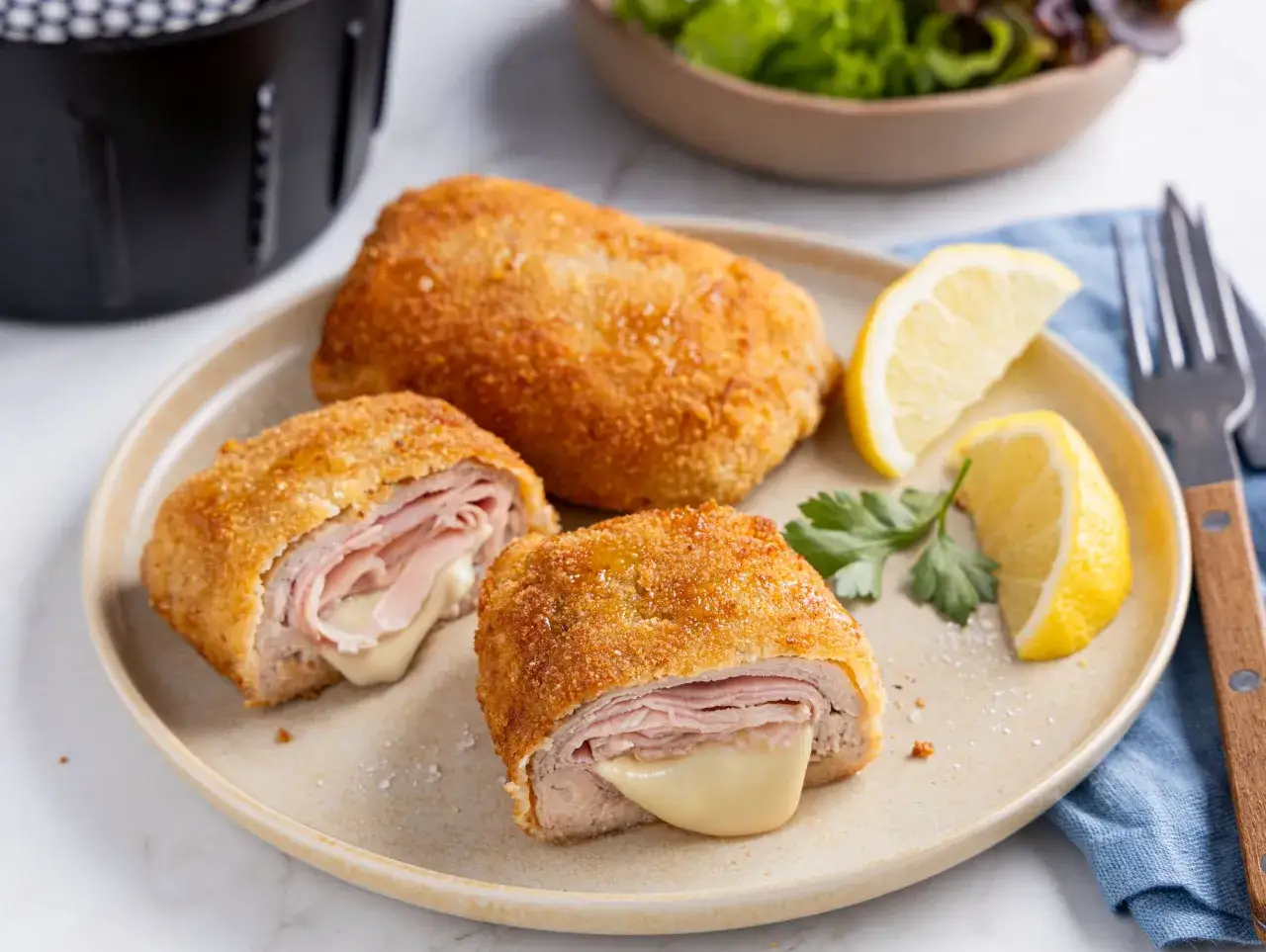 Perfektes Cordon Bleu aus dem Airfryer, goldbraun und mit geschmolzenem K&auml;se. Dazu Zitronenspalten und ein frischer Salat.