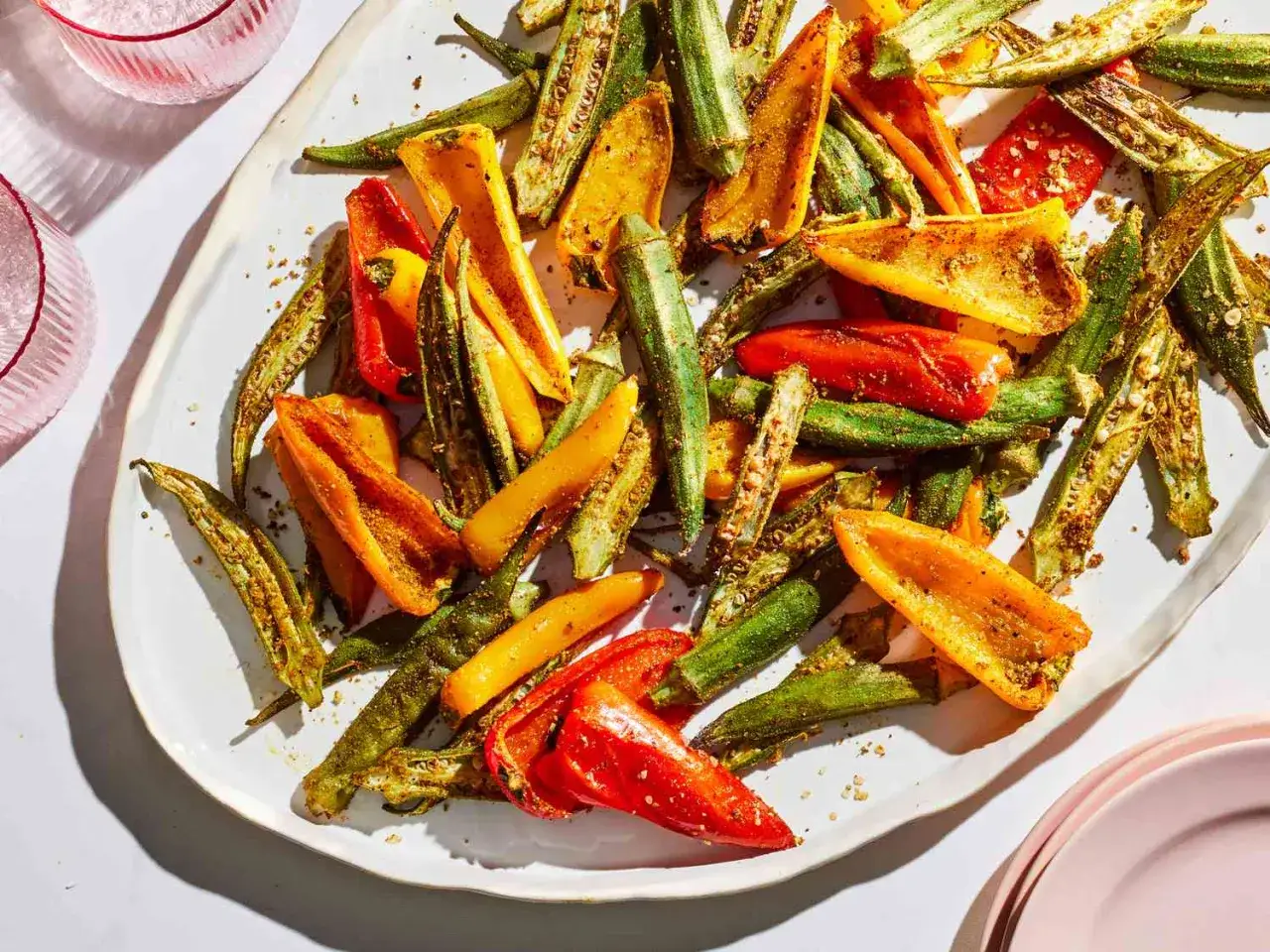 Ger&ouml;stete Okraschoten und Paprikastreifen, ein k&ouml;stliches Okra-Gericht, sind auf einem wei&szlig;en Teller angerichtet und mit Gew&uuml;rzen bestreut.