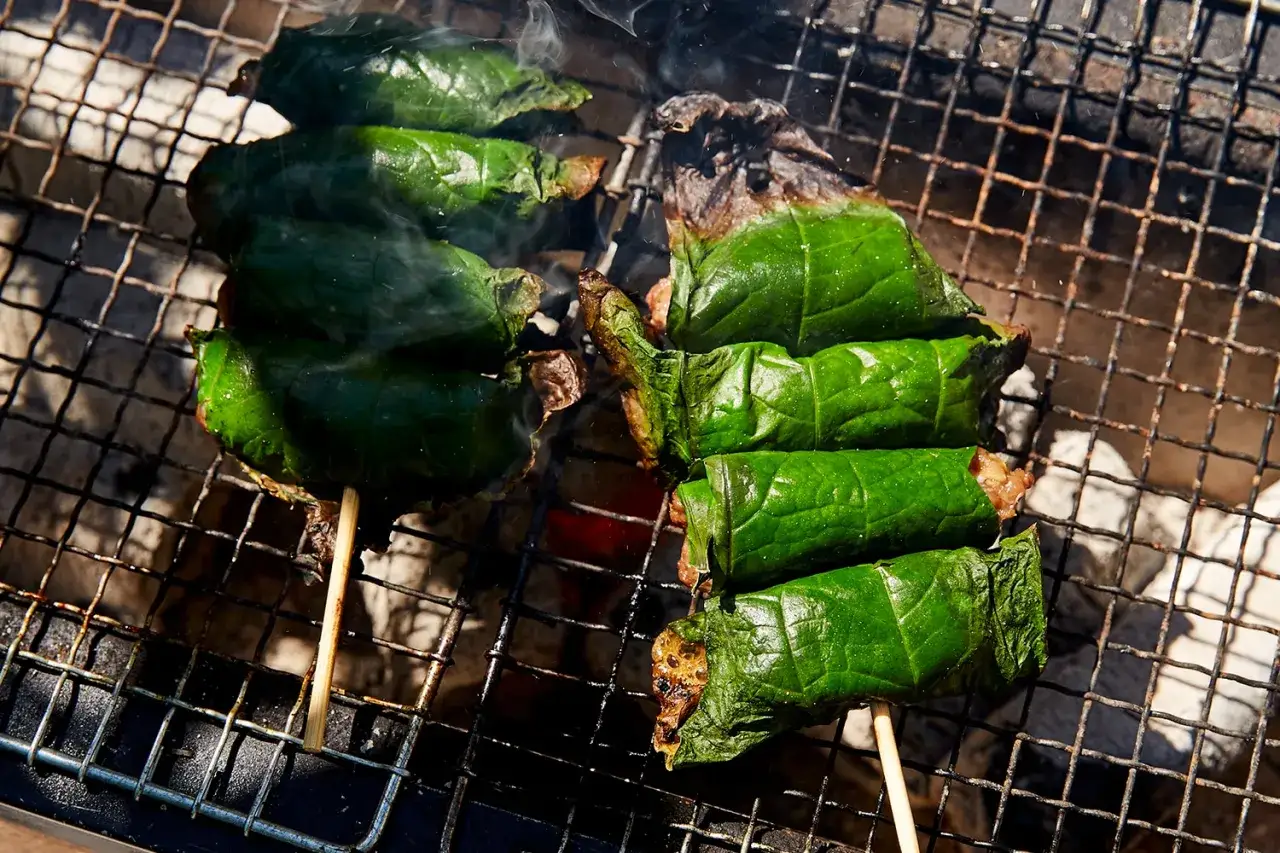 Bo la lot, gegrillt auf einem Rost, dampfend und verlockend. Fleisch umwickelt mit gr&uuml;nen Bl&auml;ttern, bereit zum Genuss.